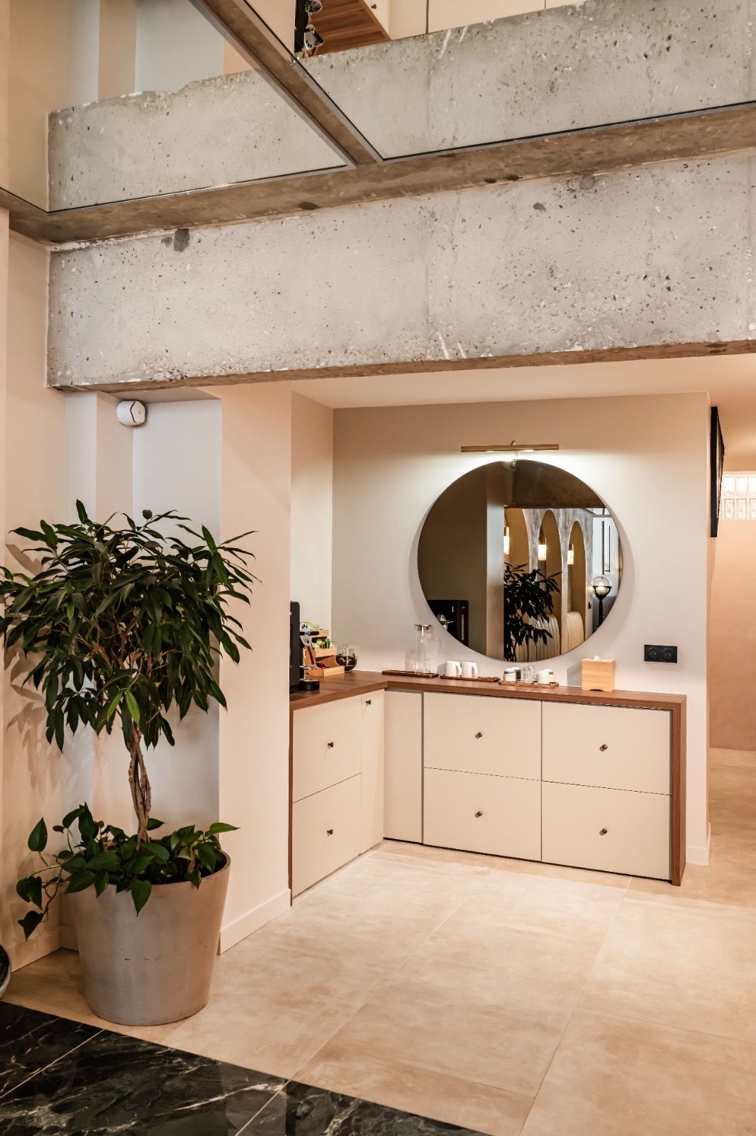 Office patients : meubles sur mesure, plan en noyer, miroir rond sous poutre béton brut